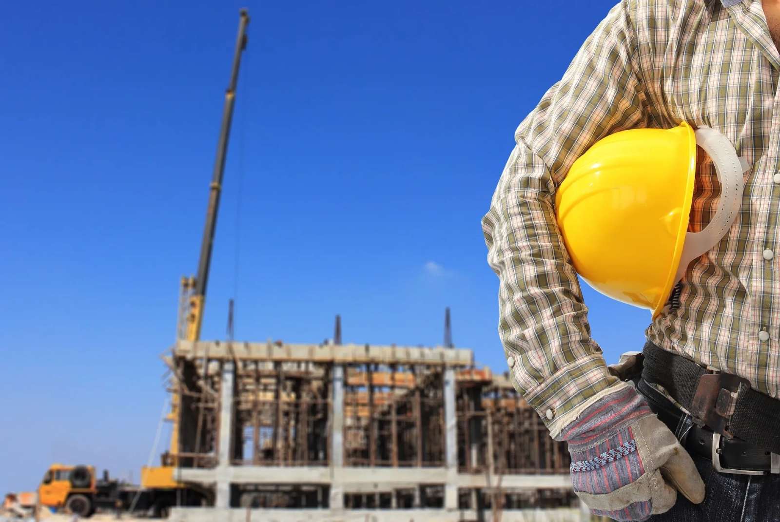 A construction worker holding onto a yellow hard hat.