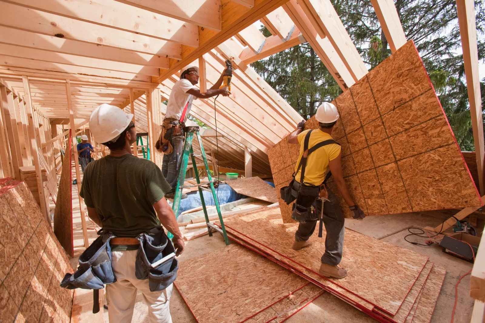 A group of men working on the roof of a house.