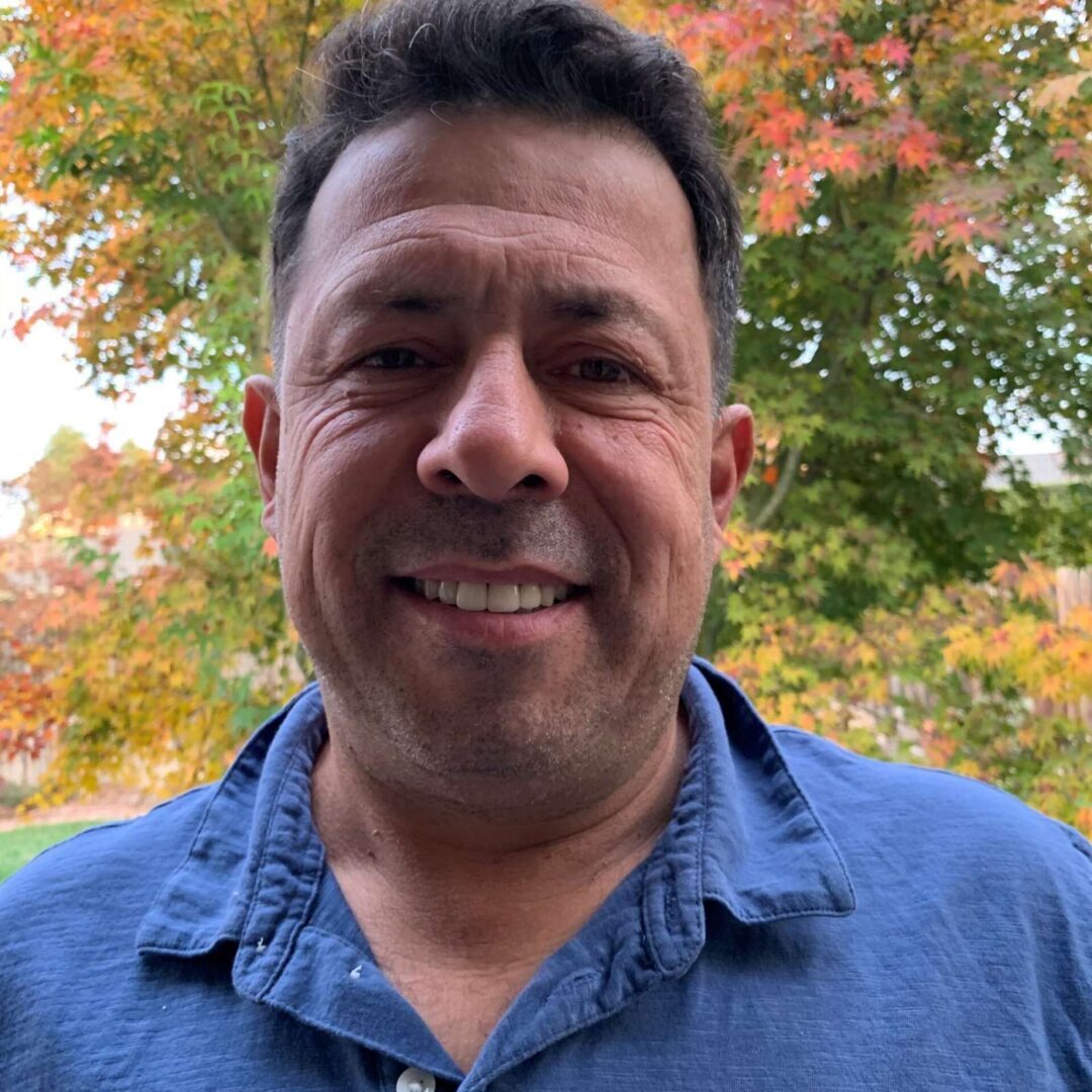 A man in blue shirt smiling for the camera.